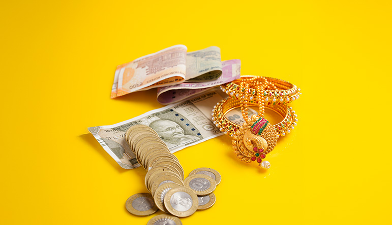Indian currency notes, coins, and gold jewelry representing personal wealth and savings.